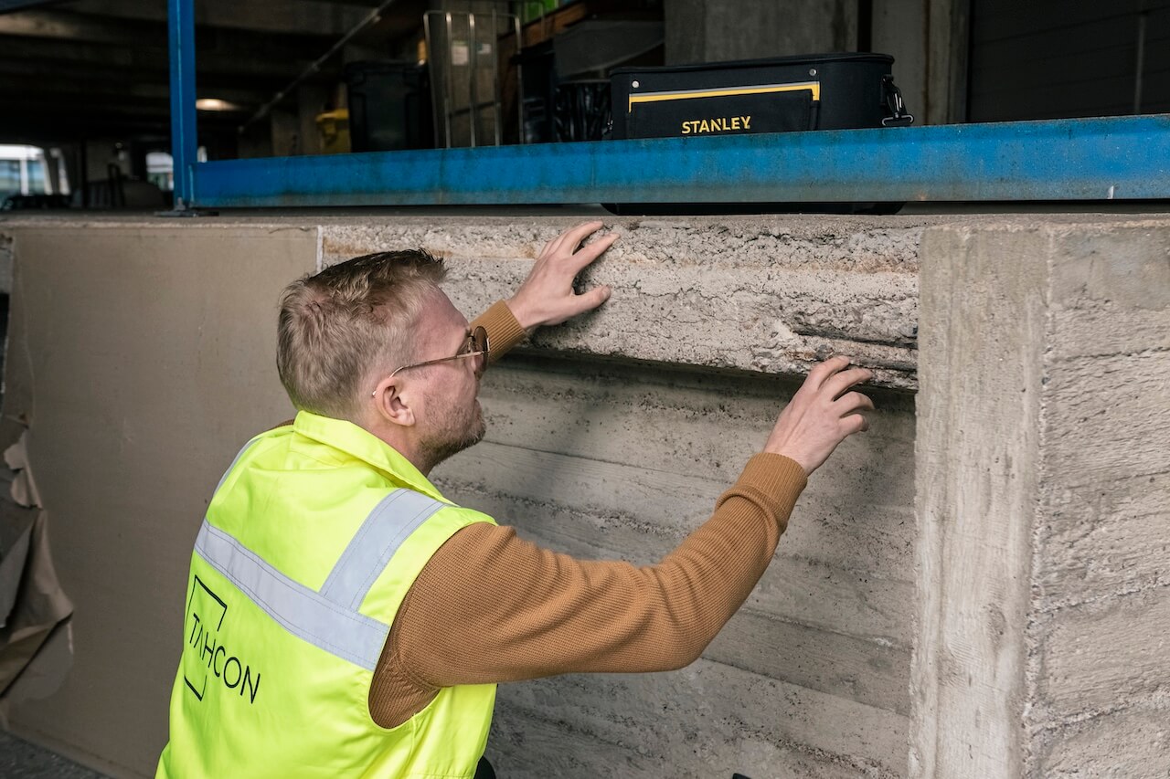 Kuntotutkija huomioliivissä tarkastelee betonirakennetta
