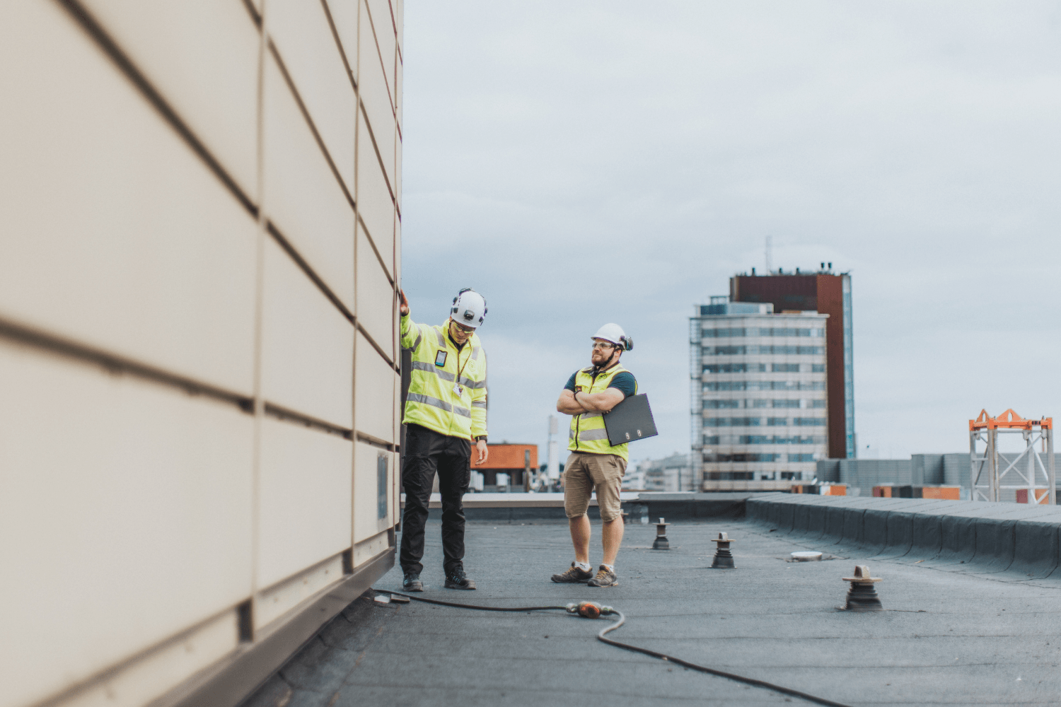 Kaksi rakennusalan työntekijää tutkimassa rakennuksen julkisivua